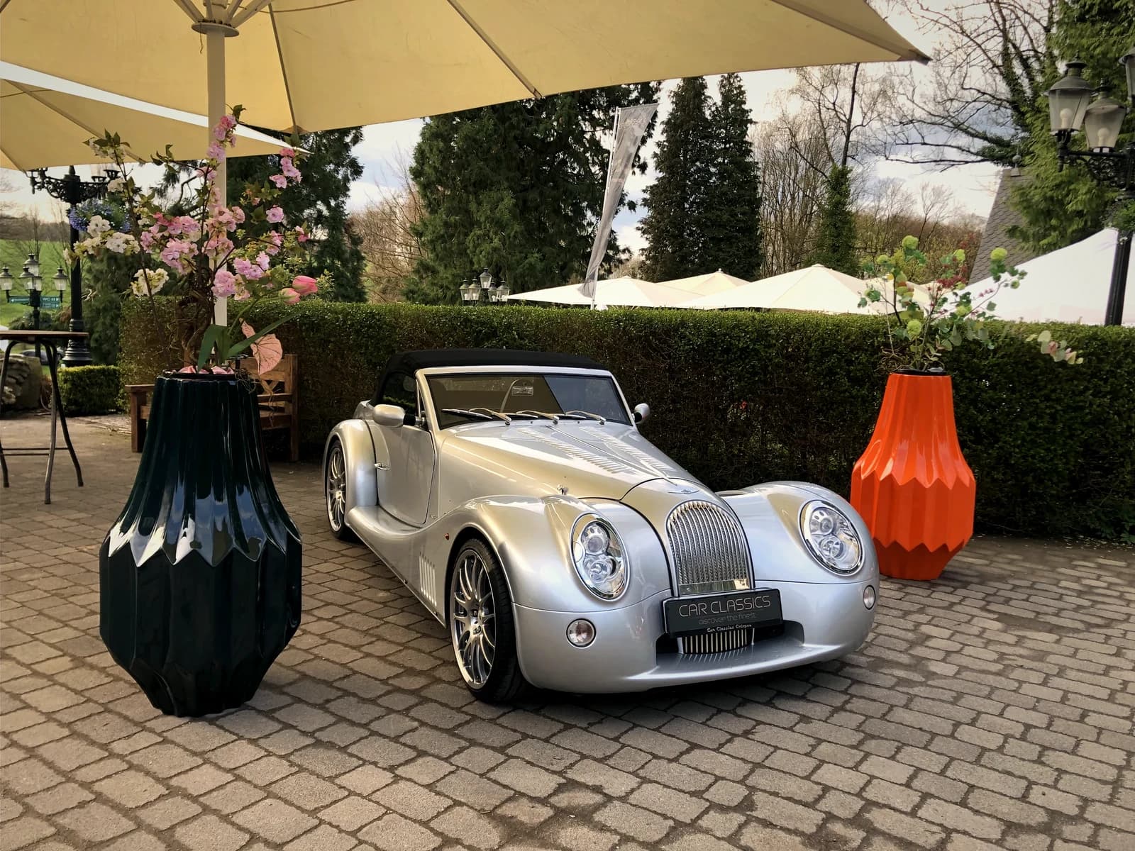 CANNELE in Schwarz-Mandarine neben Morgan Oldtimer